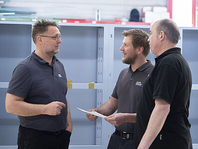 Three men are having a discussion in a room.