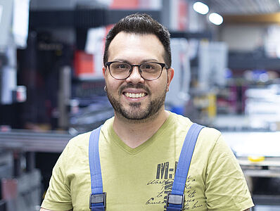 A smiling man is standing in a production hall.