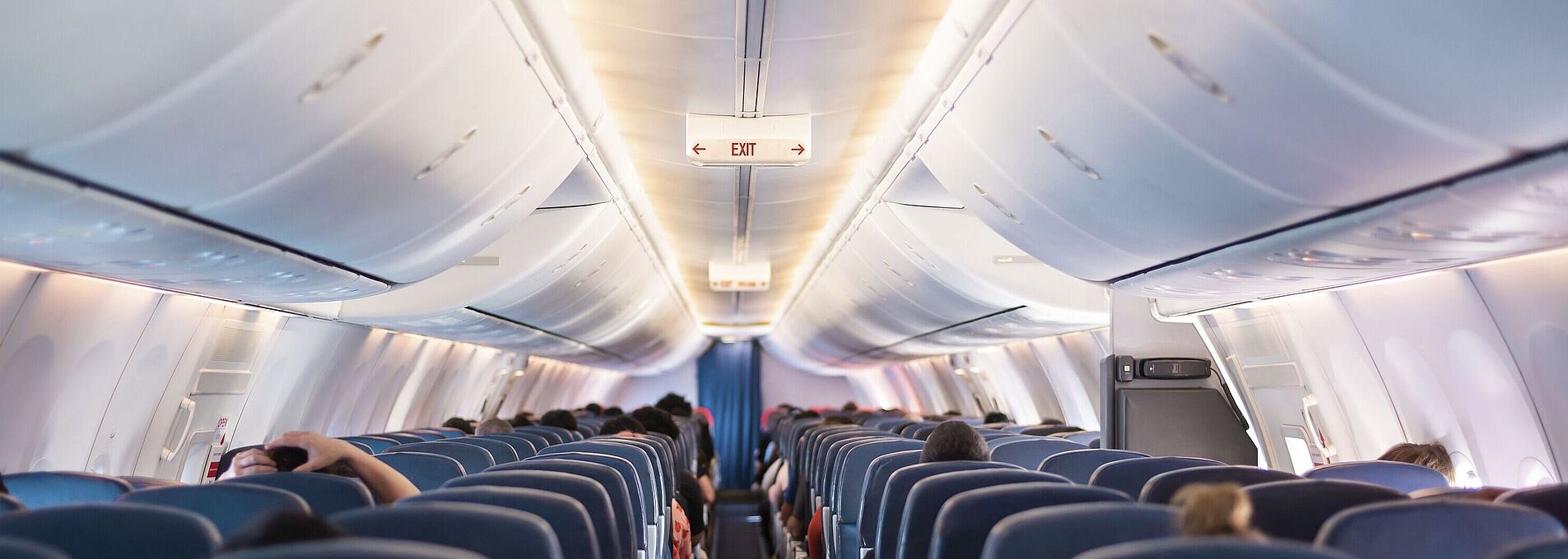 Innenraum eines Flugzeugs im Passagierbereich, gut beleuchtet. Die Ansicht zeigt die Rückenlehnen der Sitze in gleichmäßiger Anordnung.