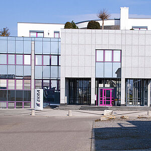 Außenansicht eines Gebäudes mit moderner Glasfront, die die Architektur und den Eingangsbereich betont.