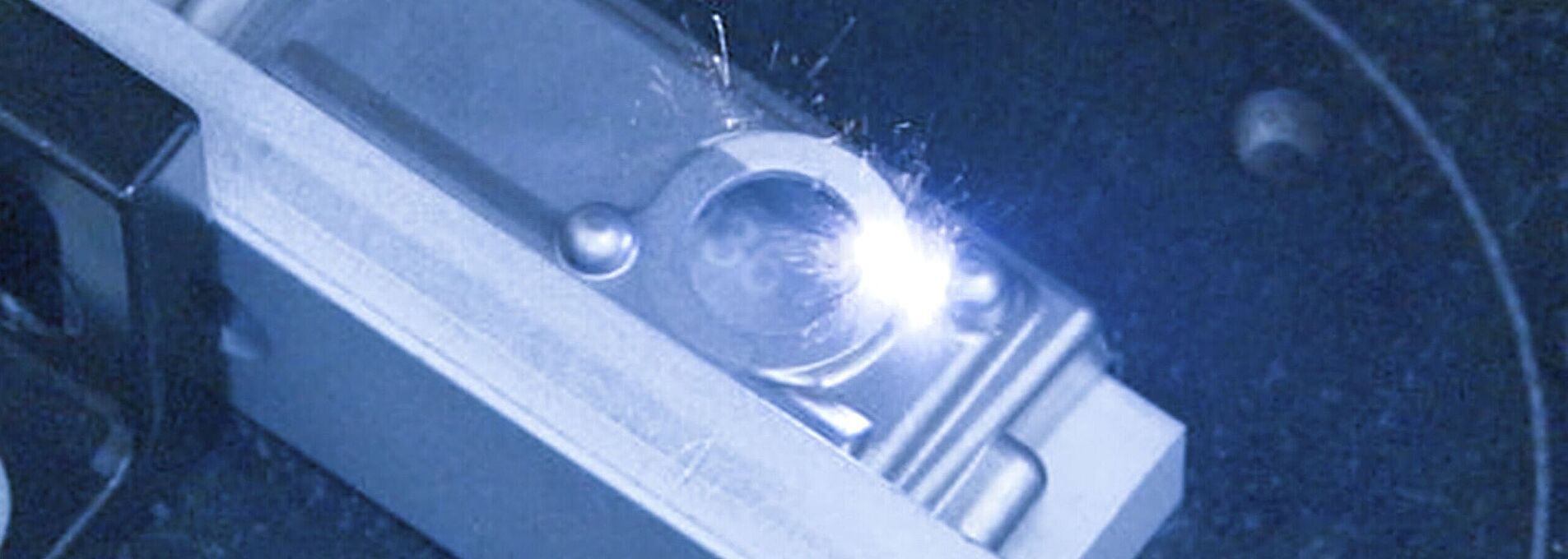 Innenansicht einer Laser Maschine, Laser trifft auf silbernes Objekt.