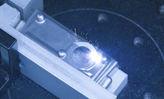Interior view of a laser machine, laser beam hitting a silver object.