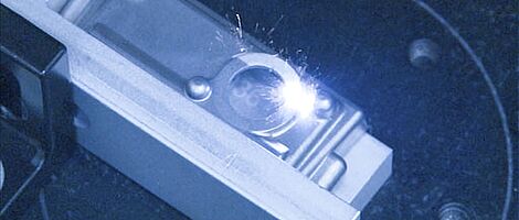Interior view of a laser machine, laser beam hitting a silver object.