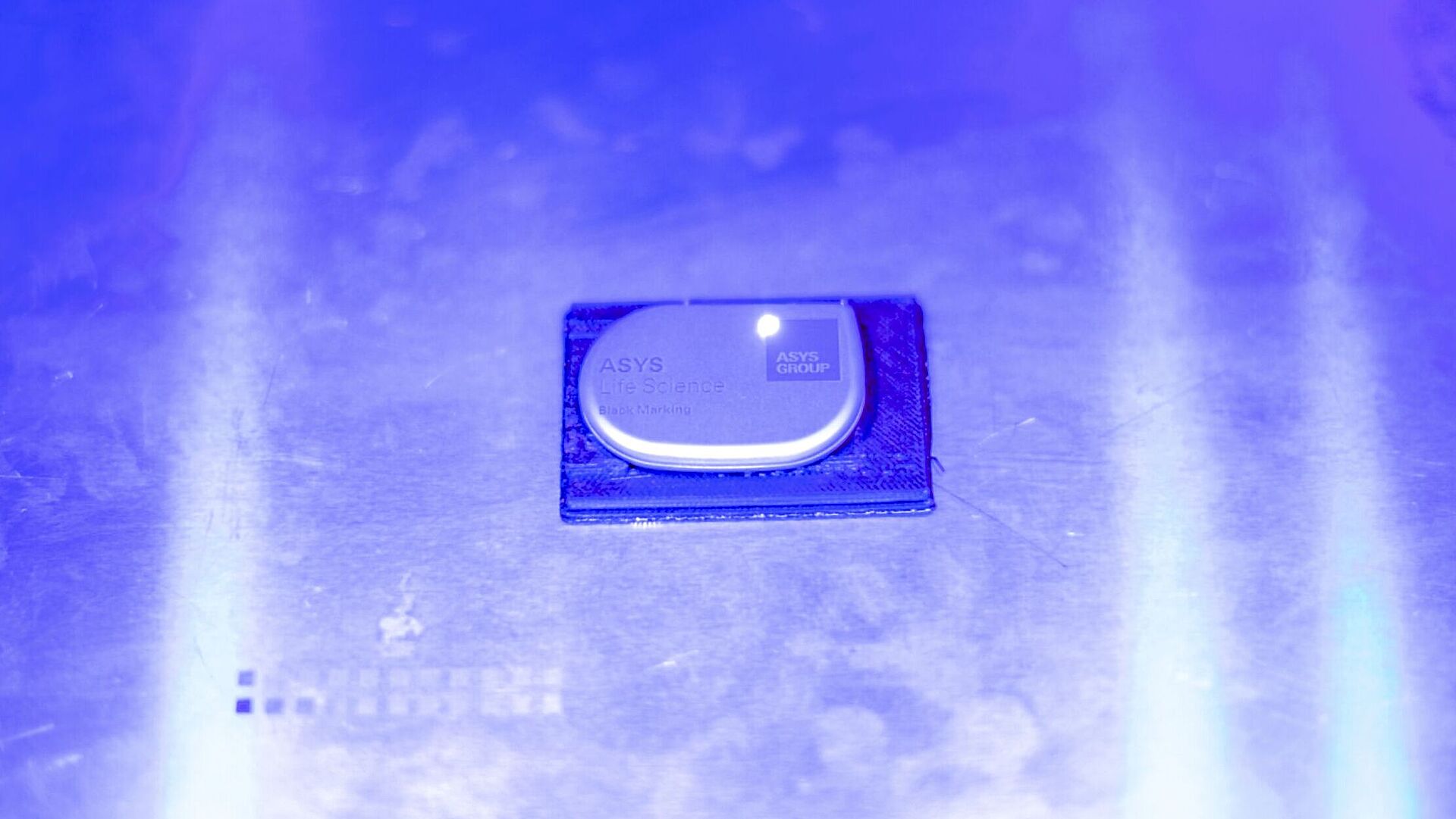 Marking chip on a silver surface in blue light.