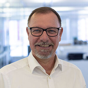 Smiling man in white shirt in a well-lid office.