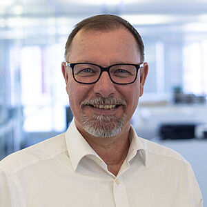 Smiling man in white shirt in a well-lid office.
