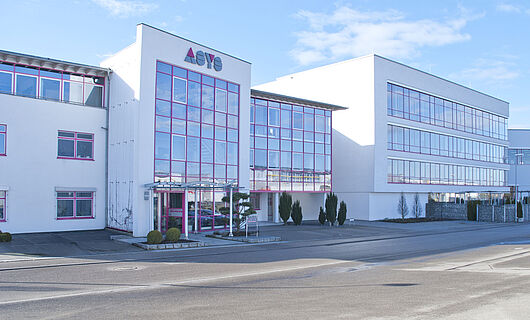 Wide view of a modern ASYS Group company building with a glass façade.