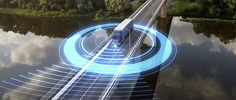 LKW fährt über eine Brücke, die einen Fluss überspannt. Im Hintergrund erstreckt sich ein dichter Wald. Um den LKW kreisen blaue, futuristisch leuchtende Lichter.