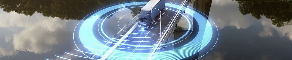 A truck drives across a bridge spanning a river. In the background, a dense forest stretches out. Blue, futuristic glowing lights circle around the truck.