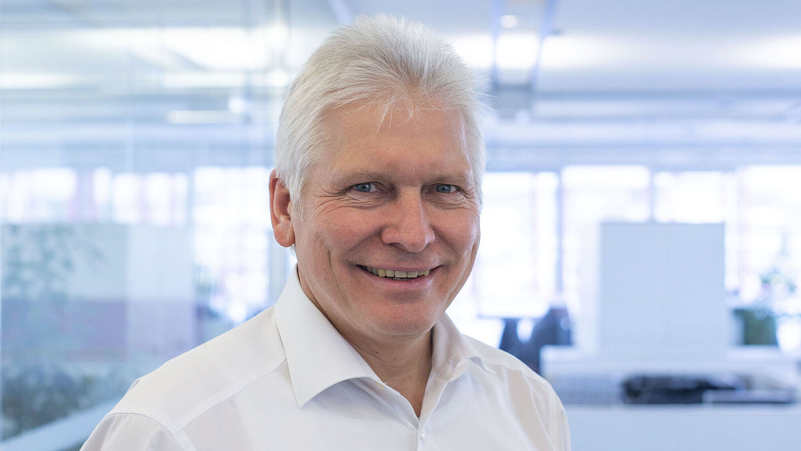 A smiling man is wearing a white shirt.
