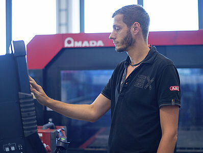 A man is operating the control panel of a laser machine.