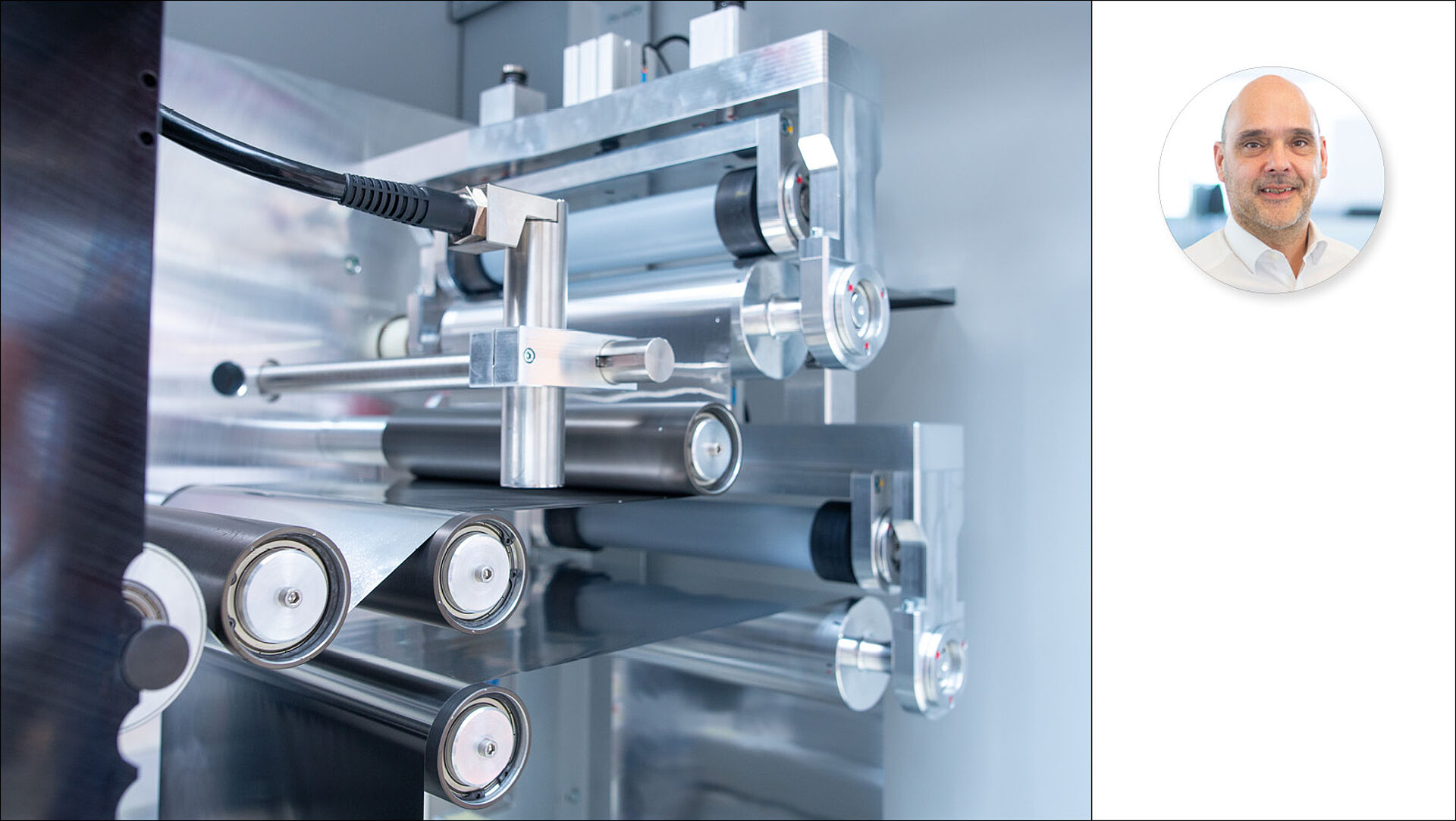 Interior view of a roll-to-roll technology system with a person pictured next to it.