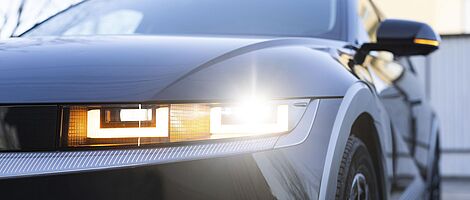 Linke Front eines modernen Autos mit Fokus auf den Scheinwerfer, der ein markantes, technisches Design zeigt.