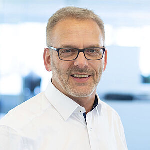 A smiling man is wearing a white shirt.
