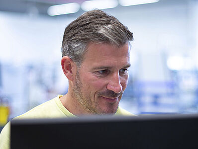 Man smiling while looking at a monitor.