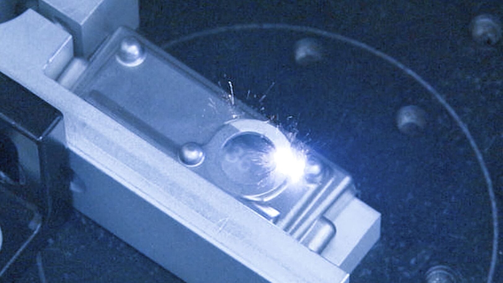 Innenansicht einer Laser Maschine, Laser trifft auf silbernes Objekt.