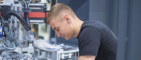 A young man is working intently on a machine.
