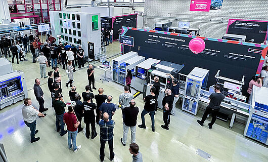 A top-down view of a production hall. Several machines and a production line. Several people in the hall.