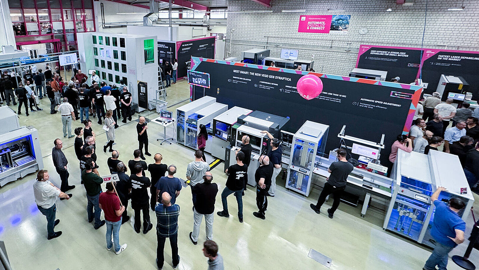 A top-down view of a production hall. Several machines and a production line. Several people in the hall.