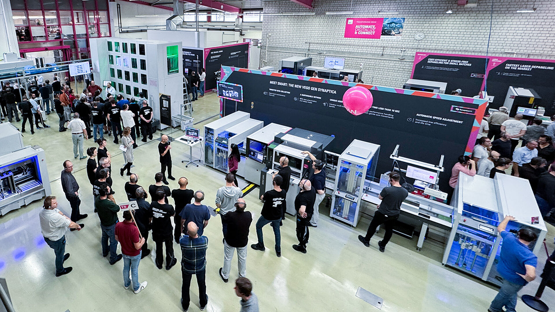 A top-down view of a production hall. Several machines and a production line. Several people in the hall.