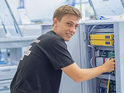 Ein junger Mann arbeitet an einer Maschine in einer Produktionsumgebung.