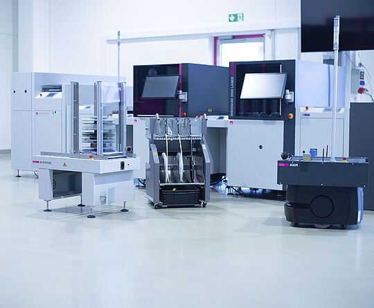 Component reel preparation for automatic placement machines. A feeder cart, M-station, and AMR in front of an SMD line.