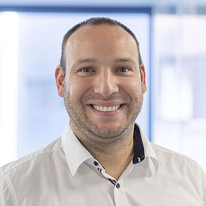 A smiling man is wearing a white shirt.