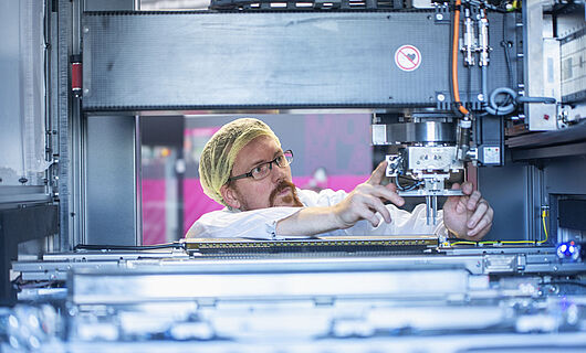 A man inspects the inner workings of a machine.