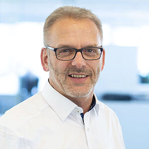 A smiling man is wearing a white shirt.