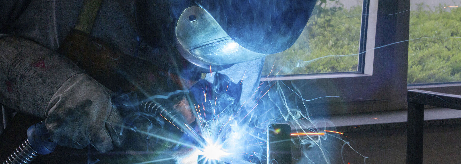 Ein Mann schweißt mit Schutzkleidung an einer Metallkonstruktion.