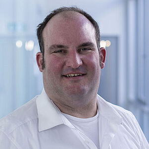 A smiling man is wearing a white shirt.