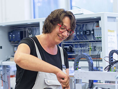 A woman is working on a machine.