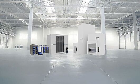 Several machines of different sizes in a huge production hall, with one person standing between them.