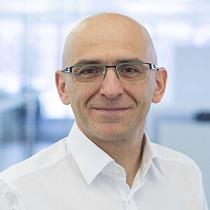 A smiling man is wearing a white shirt.