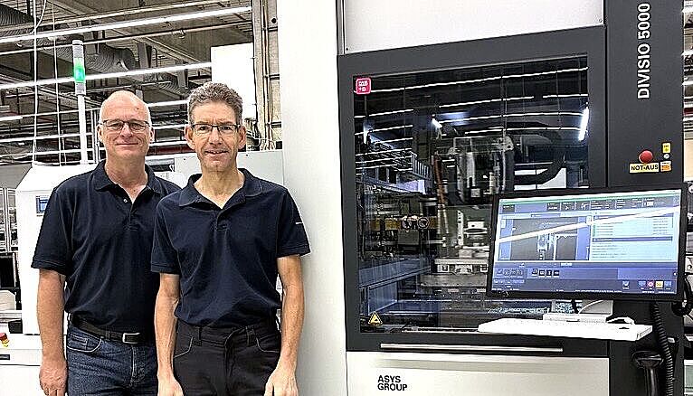 Two men standing next to a machine.