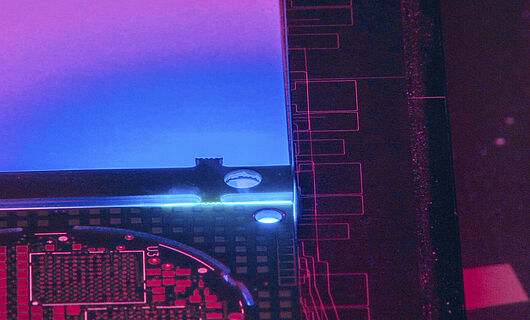 Innenansicht einer Lasermaschine mit blauem, violettem und rötlichem Licht.