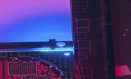 Innenansicht einer Lasermaschine mit blauem, violettem und rötlichem Licht.