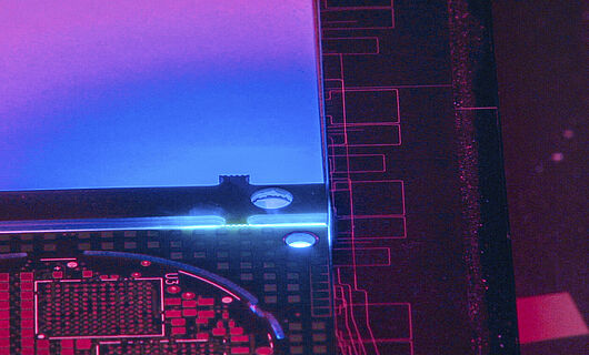 Innenansicht einer Lasermaschine mit blauem, violettem und rötlichem Licht.