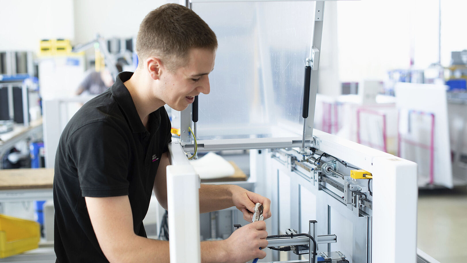 A young man is working on the inner components of a machine.