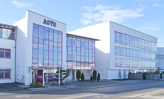 Wide view of a modern ASYS Group company building with a glass façade.