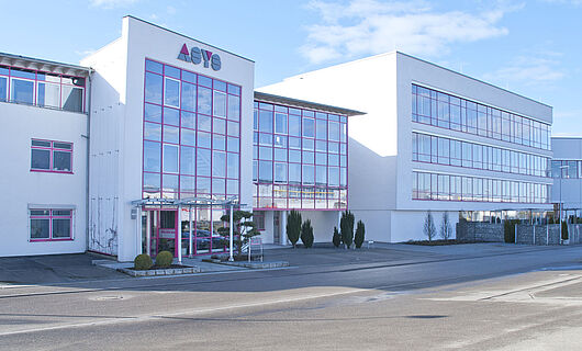 Wide view of a modern ASYS Group company building with a glass façade.