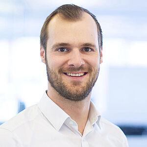A smiling man is wearing a white shirt.