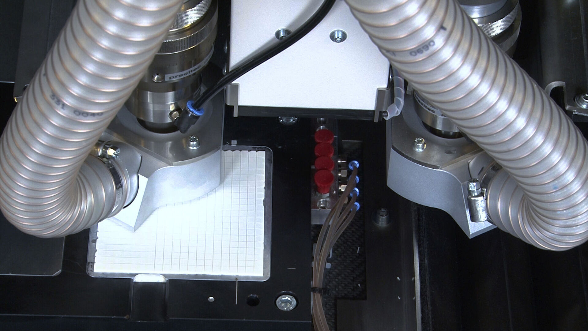Interior view of a laser machine with two large hoses and four smaller ones.