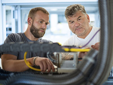 Two men working together on a machine.
