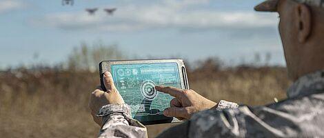 Kriegsanalytiker kontrollieren die Koordination des Militärteams mit Drohnen. Militärischer Befehlshaber mit einem digitalen Tablet-Gerät mit erweiterten Realitätstruppen im Freien.