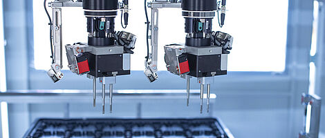 Interior view of an assembly machine featuring a dual gripper handling components with precision.