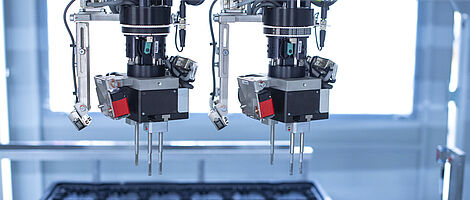 Interior view of an assembly machine featuring a dual gripper handling components with precision.