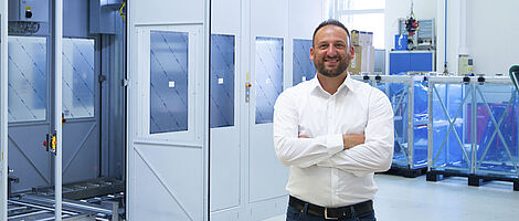 A man is standing in front of a machine with his arms crossed.