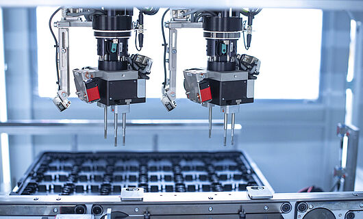 Interior view of an assembly machine featuring a dual gripper handling components with precision.