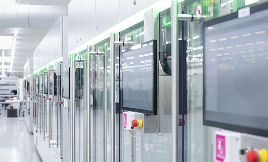 Automated production line with modern machines and touchscreens in a bright manufacturing hall.